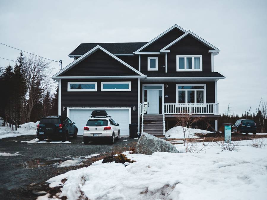 A house with its driveway and parking area cleared after a snowfall.