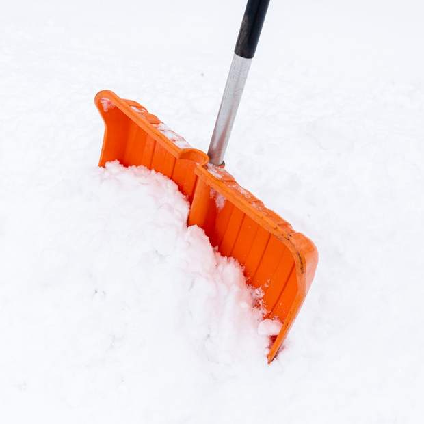 A snow shovel cutting a clean line through fresh snow.